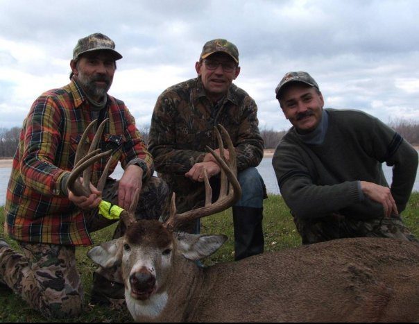 Three men posing with a dead deer