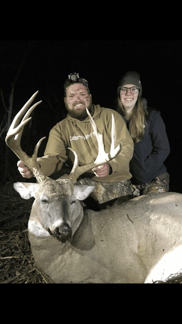 A man and a woman posing with a dead deer